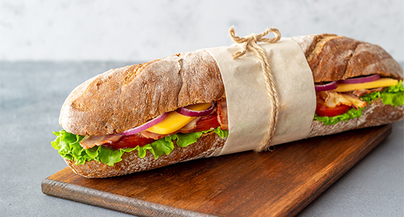 sandwich emballé dans feuille de papier sur planche en bois